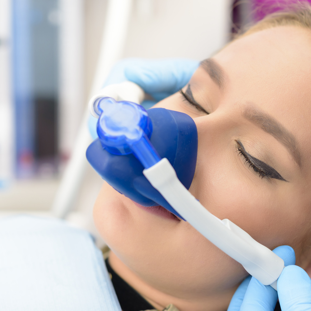 A patient breathing nitrous oxide through a nasal hood before treatment